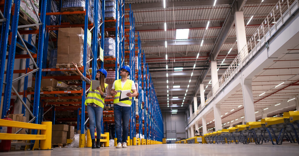Two workers survey a warehouse